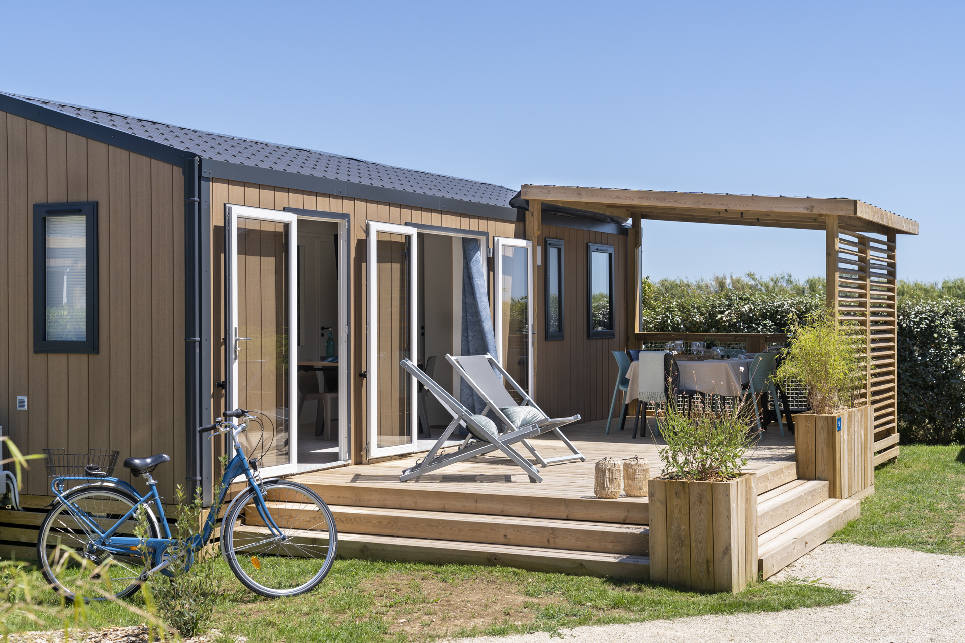 Maison mobile avec terrasse en bois et vélo bleu.