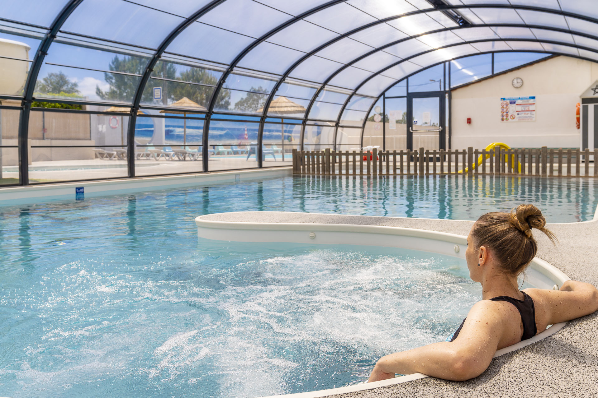 Femme relaxant dans une piscine couverte moderne.